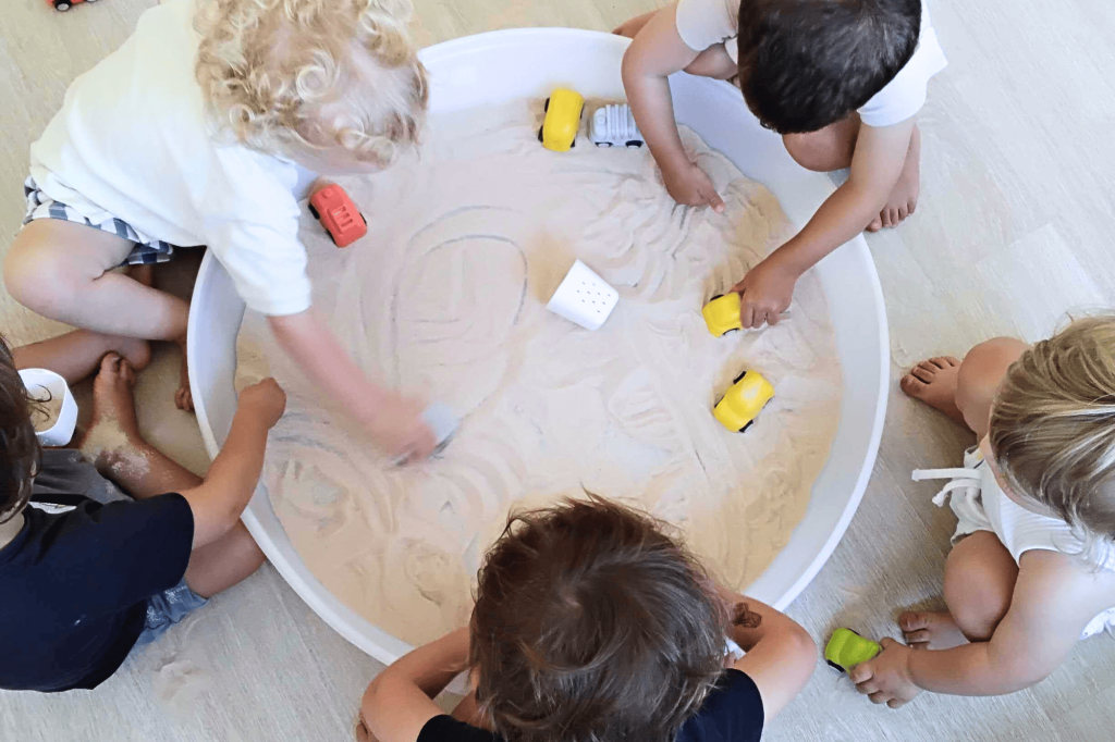 Enfants accueillis dans la crèche Nursea Perier manipulent un bac sensoriel